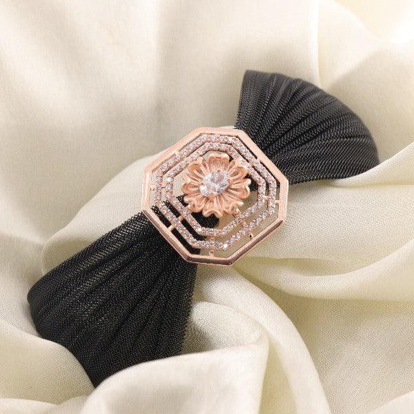 Elegant black fabric kada with rose gold floral centerpiece, embellished with a single gemstone, perfect for women.