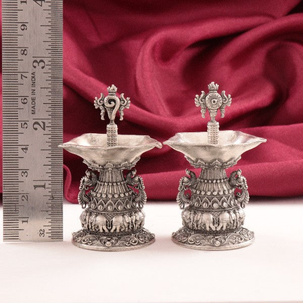 Intricately designed 925 silver 3D Shanku Chakra Deepam articles weighing 93g each, displayed with a ruler and red fabric backdrop.