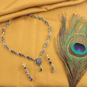 925 silver Milika women's necklace NK-203 with colorful gemstones and matching earrings on gold fabric next to a peacock feather