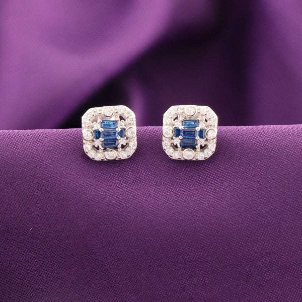 925 Silver Udita Women Studs STD-291 with blue gems against purple background.