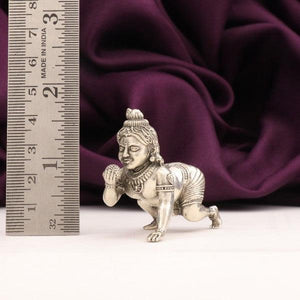 925 silver 3D Laddu Krishna idol weighing 39g and 4.5cms in length against a purple fabric and a ruler in the background