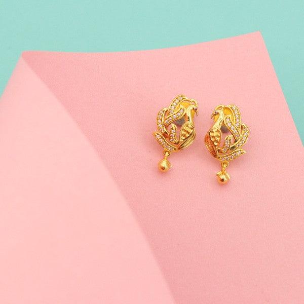 Golden peacock-shaped dangle earrings on a pastel background