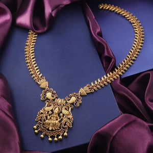 Elegant gold necklace with intricate pendant design on a dark purple silk cloth background.