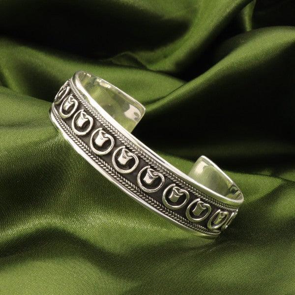 925 silver Jagjeevan men kada MKD-69 openable bracelet with intricate design on green fabric background