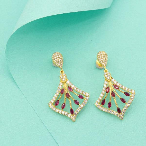 Elegant gold and ruby dangler earrings with intricate design on a mint green background.