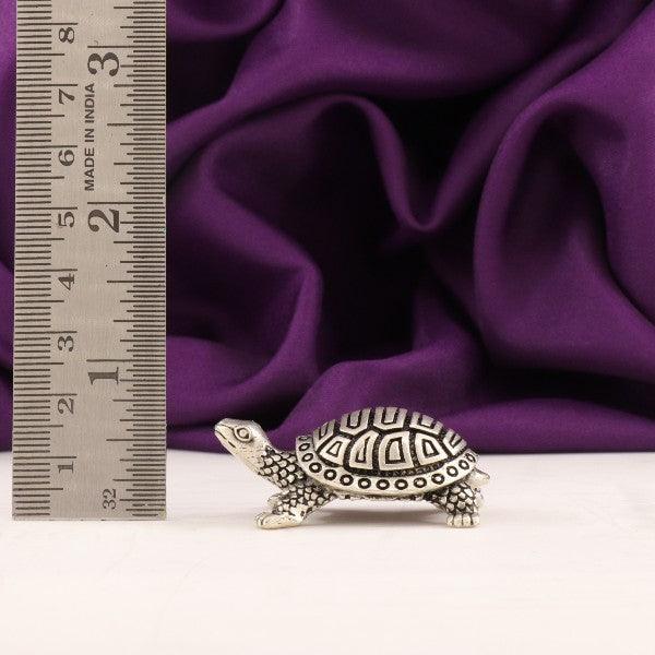 925 silver 3D tortoise idol weighing 32g and measuring 1.5cm in length, with a ruler for scale, placed against a purple fabric background.