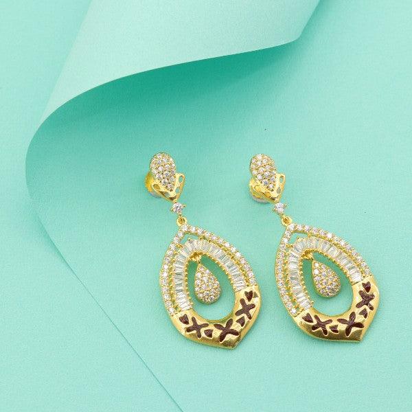 Elegant gold and diamond-shaped dangler earrings with intricate design on teal background.