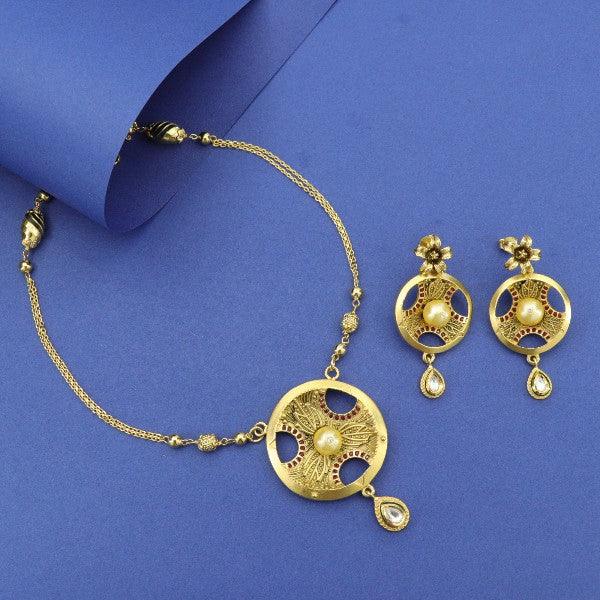 Elegant gold necklace and earrings set with intricate design and pearl accents displayed on blue background