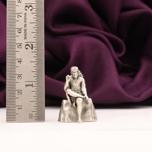 925 silver 3D Sai Baba idol with purple background and ruler for scale, weight 32g, dimensions 3.5cms, purity 925