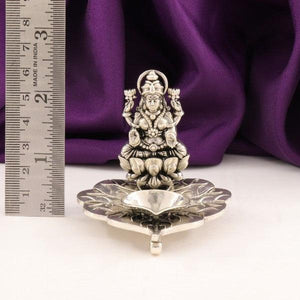 925 silver deepam featuring 2D Lakshmi design, with ruler for scale, 74g weight, 925 purity, placed against a purple fabric background.