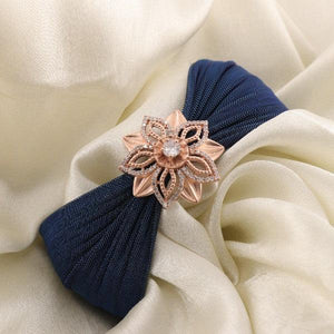 Elegant gold floral brooch on dark blue fabric with cream background