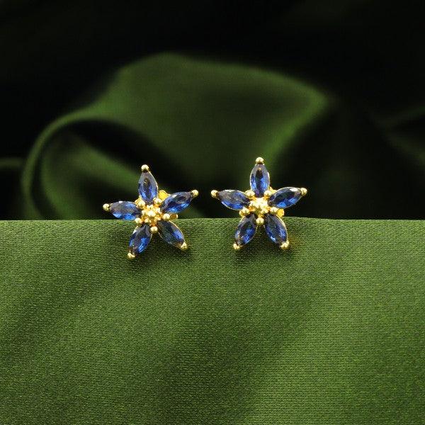 925 silver flower-shaped women's studs with blue gemstones on green velvet background